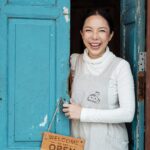 photo of woman smiling while standing on doorway
