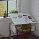 chair placed near window and table with drawings